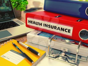 Red Office Folder with Inscription Health Insurance on Office Desktop with Office Supplies and Modern Laptop. Business Concept on Blurred Background. Toned Image.