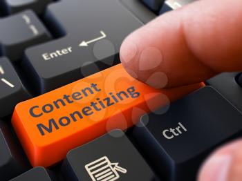 Content Monetizing Button. Male Finger Clicks on Orange Button on Black Keyboard. Closeup View. Blurred Background.