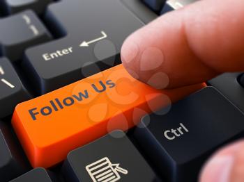 Follow Us Button. Male Finger Clicks on Orange Button on Black Keyboard. Closeup View. Blurred Background.