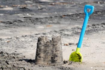 Sand castle and a plastic shovel at a beach