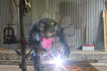 Man welding a piece of iron on a work table in a shop