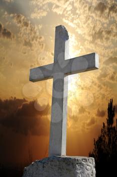 White concrete cross with a beautiful sunrise as background