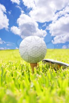 Golf  ball on a tee  against a bright blue sky in the background