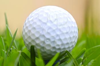 Macro shot of a golf ball on lush green grass