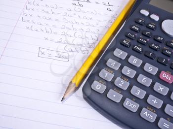 Macro shot of a calculator over a page with a math problem and a yellow pencil