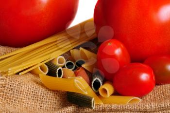 macro shot of pasta and tomatoes over a brown cloth bag