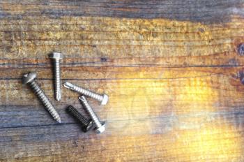 Macro shot of several screws on a wooden table