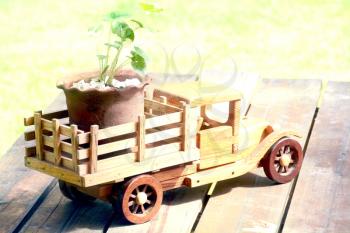 Wooden toy truck carrying a plant on top of a table