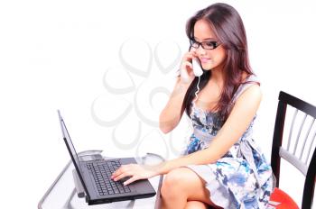 Beautiful young girl talking on the phone and working on a laptop