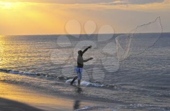 Young fisherman throwing a fishing net into the ocean