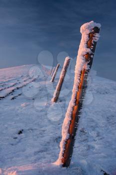 The repetition posts on the snowy hill are dividing the space.