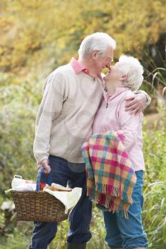 Romantic Senior Couple Outdoors With Picnic Basket By Autumn Woodland