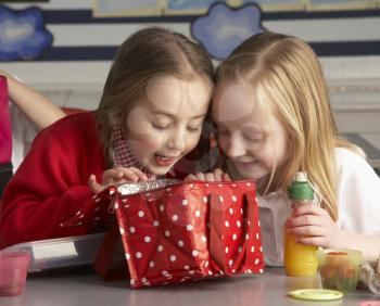 Primary School Pupils Enjoying Packed Lunch In Classroom