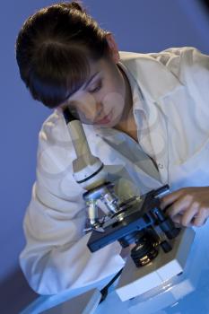 A beautiful female medical or scientific researcher using her microscope.