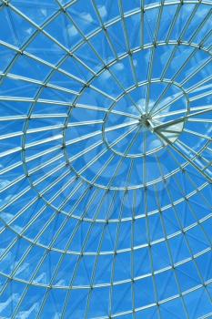 Bright blue sky seen through a modern architecture round or spiral window.
