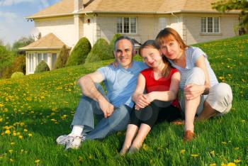 Portrait of a happy family of three on the lawn on front of their house