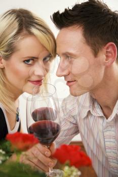Young couple romantic dinner: clinking glasses with red wine
