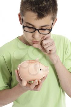 A boy holding a money box is thinking or pondering, eg finance, savings, spending.