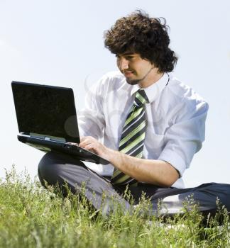 Portrait of young businessman doing computer work in the park