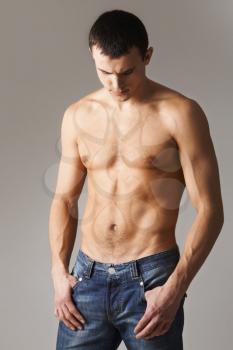 Image of shirtless man in jeans isolated over grey background