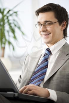 Image of happy businessman typing on laptop with smile
