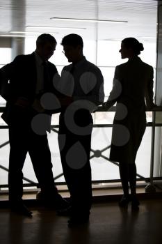 Figures of three business partners standing on balcony and interacting with each other