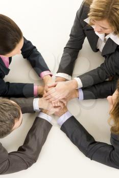 Image of business people keeping hands on top of each other at workplace