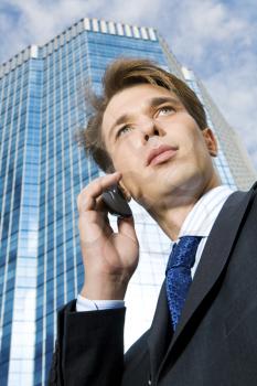 View from below of confident businessman speaking on the phone outdoors