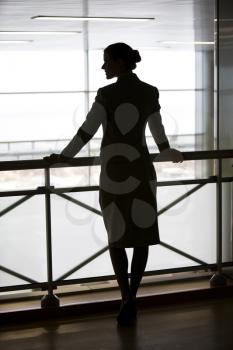 Silhouette of business lady�s back standing on the balcony and touching its railing