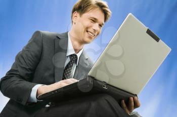 Successful young smiling businessman sees a plan the decision of a question in the laptop