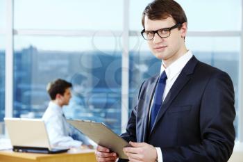 Portrait of smart businessman holding with glasses in working environment
