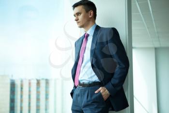 Portrait of confident man looking through window in office