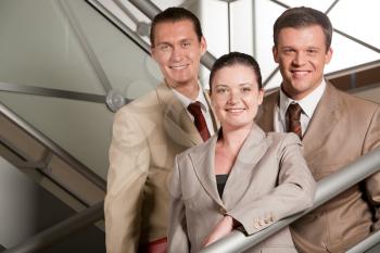 Portrait of positive business group standing on stairs of modern building