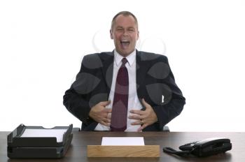 Businessman sat behind a desk laughing. Concept of Helpdesk, Customer service, Complaints Dept etc