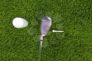Photo of an iron hitting a golf ball off the tee with motion blur on the club and ball. Actual shot not photoshopped in.
