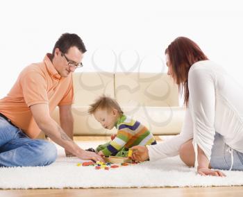 Family with baby boy ( 2 years old ) sitting on floor at home and playing together.