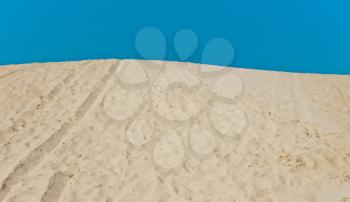 Sand dune with footprints on blue sky background