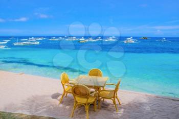 Wooden table and chairs on tropical beach with blue sea