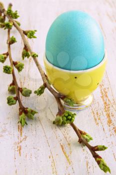 Turquoise egg in a yellow ceramic stand on the board