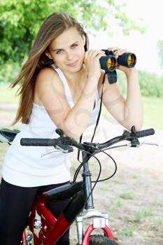 Young girl on bicycle with binoculars in hand