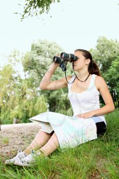 Woman with binoculars on the banks of the river studying a map