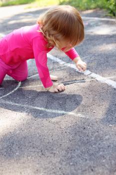 Little girl draws a large sun on asphalt
