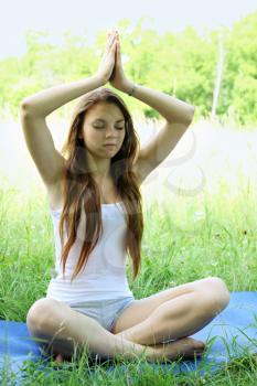 Young beautiful woman practices yoga in nature