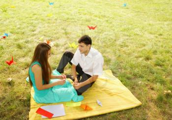 man and woman relaxing on nature make origami