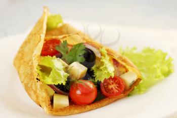 Pancake stuffed with salad, cheese, tomatoes and olives