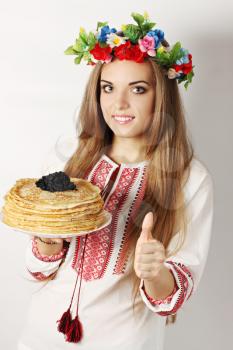 Ukrainian woman holds a plate of pancakes and caviar showing ok gesture