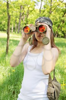 Young woman looking through binoculars on the nature