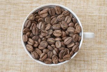 Cup with coffee beans on sacking