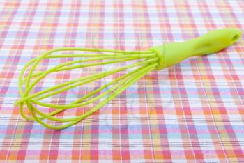 Whisk on a checkered tablecloth.