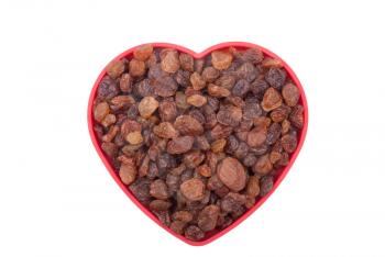 Raisins in a bowl in the shape of a heart on a white background.